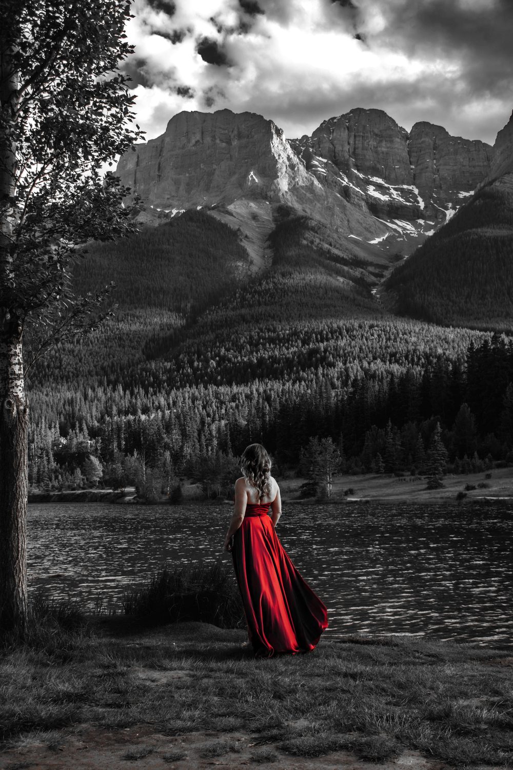 Julia standing at the edge of a mountain lake in a red gown