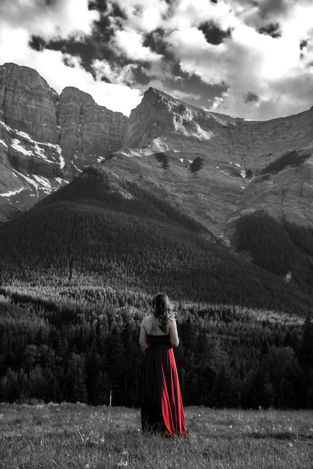 Julia in a red gown in a meadow beneath a towering limestone peak